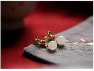 Detailed macro view of 925 silver Hetian jade earrings with blue enamel cloud patterns