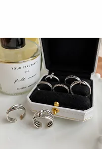 Primer plano de anillos de plata vintage trenzados y anudados en joyero blanco