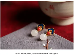 Macro detail of Hetian jade and red agate earrings with blue enamel cloud pattern