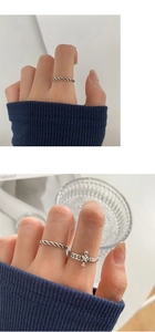 Primer plano de anillos apilables de plata vintage trenzada en una mano femenina