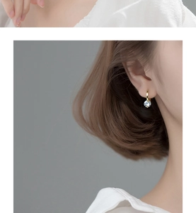 Close-up of minimalist gold hoop earring with a round clear zircon drop on a model
