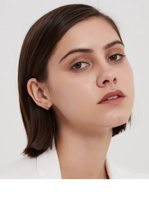 Gros plan de boucles d'oreilles créoles dorées en argent s925 avec motif quadrillé
