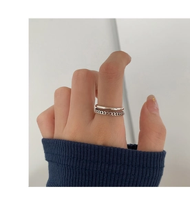 Detalle del anillo de cadena de plata y la banda lisa minimalista usados en el dedo