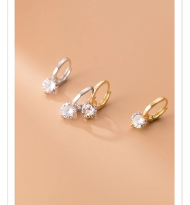 Detailed view of silver and gold huggie earrings with round-cut sparkling cubic zirconia
