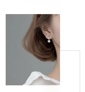 Minimalist sterling silver earrings with round cubic zirconia worn on a model's earlobe
