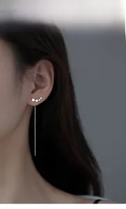Elegant star drop earrings with long silver tassels shown on a model's ear