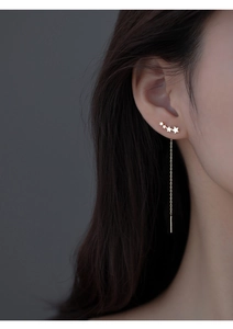 Close-up of golden star tassel earrings with curved star design and long chain drops