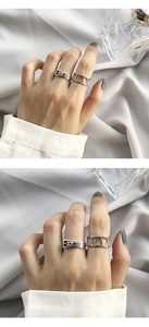 Close-up of silver belt buckle and Roman numeral cutout rings worn by a model