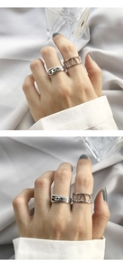 Close-up of silver hollowed Roman numeral ring and vintage buckle belt style ring set