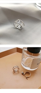 Detailed view of hollow Roman numeral silver ring and pearl band on satin fabric