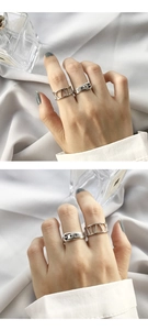 Close-up of silver belt buckle ring and Roman numeral band worn on the finger