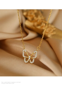Detail einer goldenen Schmetterlingskette mit Zirkonia-Diamanten auf elegantem Seidenstoff