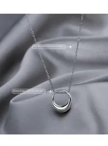 Macro detail of a polished sterling silver circle pendant on a fine necklace chain