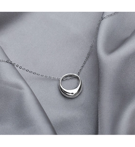 Detailed close-up of a silver geometric circle necklace on grey satin background