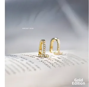 Gros plan de boucles d'oreilles dorées en T serties de zircons sur un livre ouvert