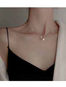 Detail of minimalist silver geometric circle pendant on a delicate chain for women