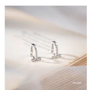 Vue macro de boucles d'oreilles en T en argent avec zircons et détail du poinçon S925