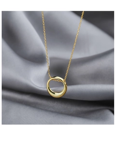 Close-up of minimalist gold geometric circle pendant on silk background with light shadows