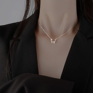 Elegante Halskette mit Schmetterlingsanhänger und Zirkonia-Steinen getragen auf schwarzem Sakko