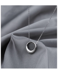 Minimalist silver geometric circle pendant necklace on grey silk satin background