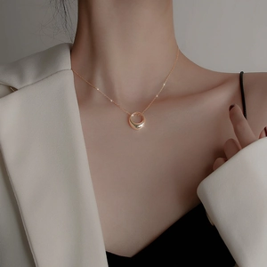 Elegant gold minimalist necklace with circular pendant on a model wearing a blazer