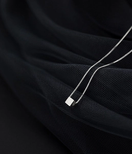 Macro detail of a brushed S925 silver cube pendant on a fine box chain necklace
