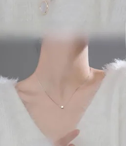 Close-up of a S925 sterling silver cube necklace worn on a soft white sweater neck