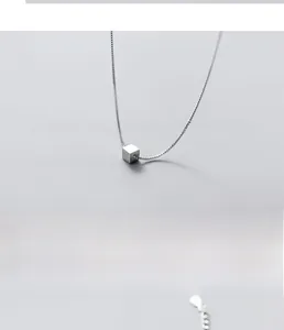 Detailed macro view of minimalist S925 sterling silver cube pendant on a fine link chain