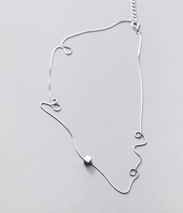 Macro detail of silver geometric cube pendant and adjustable lobster clasp chain