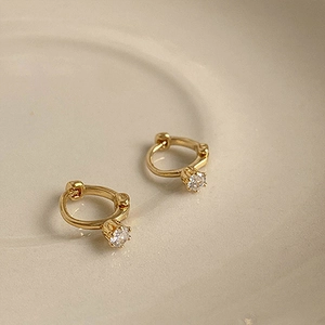 Aros dorados minimalistas con una piedra de circón redonda en un engaste clásico de 4 garras