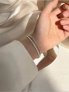 Close-up of a double-layer silver beaded bracelet on a wrist with silk background