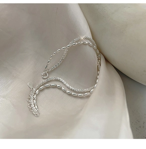 Close-up of silver double-layered bracelet with olive beads on white silk fabric