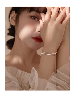 Close-up of a double-layered silver chain bracelet with olive beads on a woman wrist