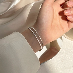 Minimalist double-layered silver bracelet with delicate beads on a silk background