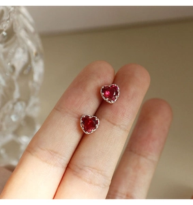 Macro view of heart-shaped S925 silver stud earrings with red cubic zirconia stones
