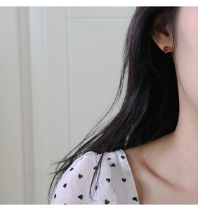 Detailed close-up of a heart-shaped red zircon stud earring on a female model