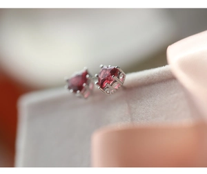 Macro detail of S925 sterling silver heart-shaped earrings with red zircon in a gift box