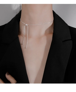 Minimalist silver snake chain choker with dangling metal beads on a black suit model