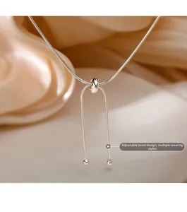 Close-up of adjustable slider bead on silver snake chain necklace with silk background