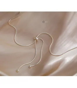 Close-up of adjustable silver snake chain necklace with sliding bead clasp on silk fabric