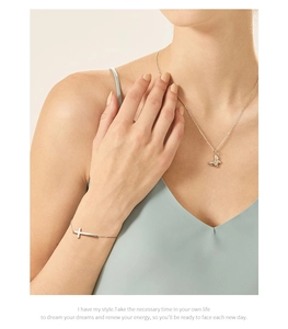 Dettaglio di una collana d'argento con farfalla e bracciale con croce indossati al polso