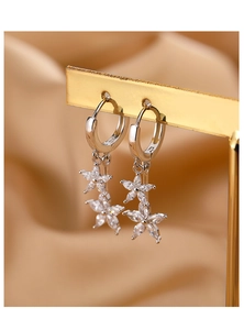 Détail de boucles d'oreilles créoles fleurs en argent et zircons sur soie champagne