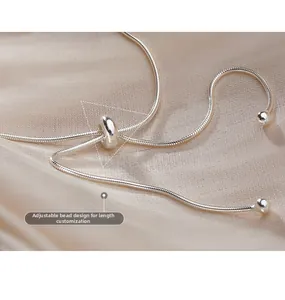 Detail of adjustable slide bead on silver snake chain necklace with silk backdrop