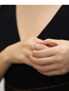 Close-up of golden square-cut zircon ring worn on finger with elegant dark background
