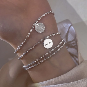 Close-up of a silver beaded multi-layer bracelet featuring a Lucky charm on a wrist