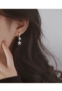 Gros plan d'une mannequin portant des créoles fleurs en argent avec zircons et pétales marquise