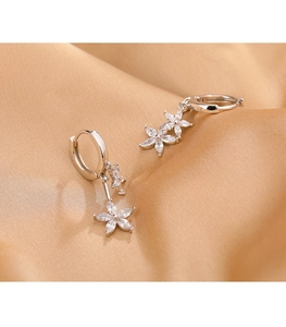 Gros plan de boucles d'oreilles fleurs en argent et zircons sur satin de champagne