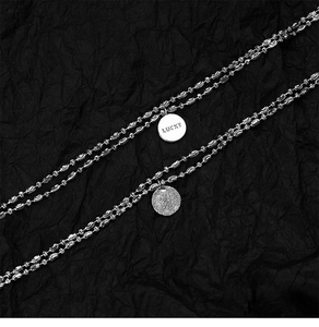 Detailed macro view of silver necklace with LUCKY engraving and textured coin charms
