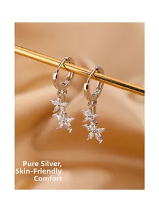 Détail de boucles d'oreilles fleurs en argent S925 et zircons sur fond de soie dorée