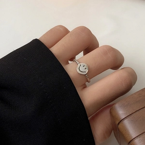 Close-up of beaded silver ring featuring a black cutout smiley face on the index finger